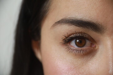 Woman's hazel eye, light brown, black eyelashes, looking at the camera.