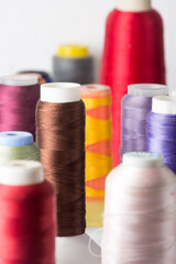 close-up of spool of sewing threads used in fabric and textile industry, different colors, soft-focus background