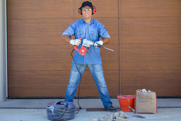Image of a construction worker posing with demolition hammer and tools of the trade. Handyman and...