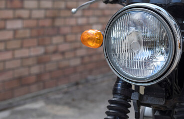 glass headlight of a motorcycle on the background of a brick wall