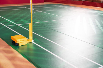 Yellow weighted pole badminton net base was placed on the side of a badminton court.