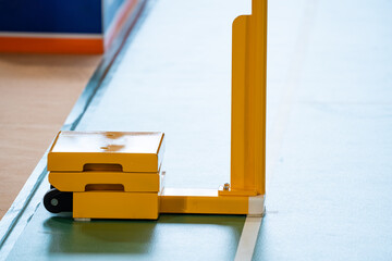 Yellow weighted pole badminton net base was placed on the side of a badminton court.