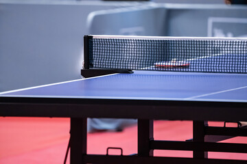 Blue and smooth surface table tennis table with tight black net to being prepared for practice and competition.