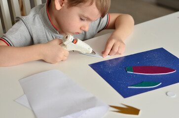 boy glyes a craft with a glue gun
