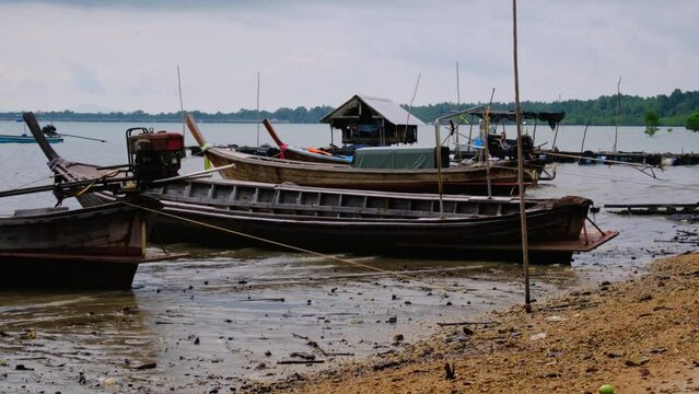 Fishing boats moored in a local fishing jetty on Yao Yai Island, Phang Nga, Thailand. fishing boats at the beach and waves.