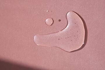 Fototapeta premium A drop of cosmetics or perfume on a pink background.