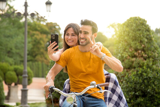 Couple taking a selfie while riding a bike in a park
