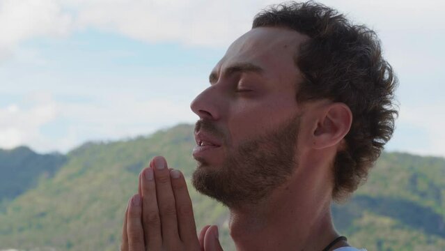 Headshot of a serene Caucasian man praying to god, meditating in the mountains, taking conscious breaths towards a better life. Personal spiritual growth, achievement, motivation, self-improvement