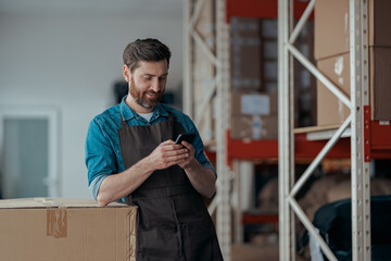 Man worker in uniform standing on coffee warehouse and using mobile phone