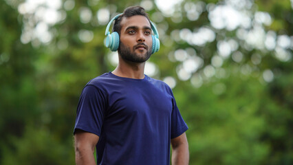 Naklejka premium a man standing in the park with headphones in his ear