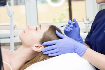 A woman receiving an injection into the scalp at a beauty center.