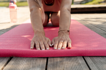 Woman stretching on yoga mat close up. Focus on hands