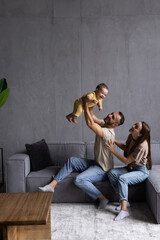 Naklejka premium Happy young parents play have fun with excited little son in living room.