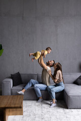 Young happy family mother father and kid having fun at home on the couch