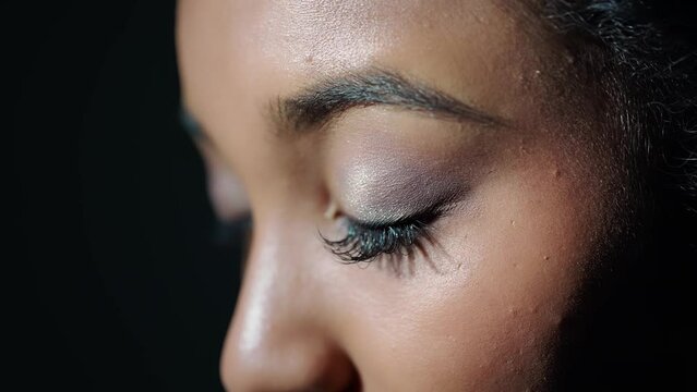 Young African woman opening eyes in dark room.