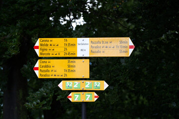Hiking trail direction signs at mountain station of local mountain San Salvatore on a cloudy summer day. Photo taken July 4th, 2022, Lugano, Switzerland.