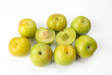 Small mini green fresh juicy plum fruit on white background cut slice half seed many pile