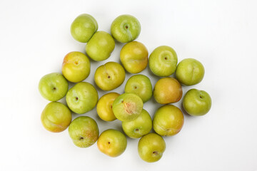 Small mini green fresh juicy plum fruit on white background cut slice half seed many pile