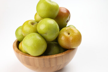 Small mini green fresh juicy plum fruit in wooden bowl on white background cut slice half