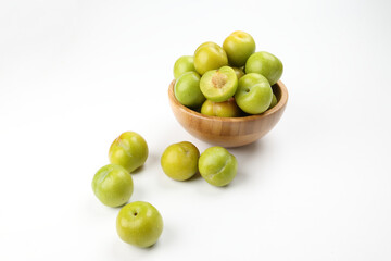 Small mini green fresh juicy plum fruit in wooden bowl on white background cut slice half