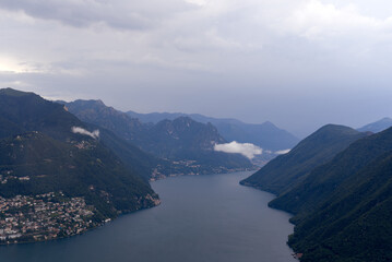 Fototapeta na wymiar Aerial view from local mountain San Salvatore over region of Lugano, Canton Ticino, with Lake Lugano on a cloudy summer day. Photo taken July 4th, 2022, Lugano, Switzerland.