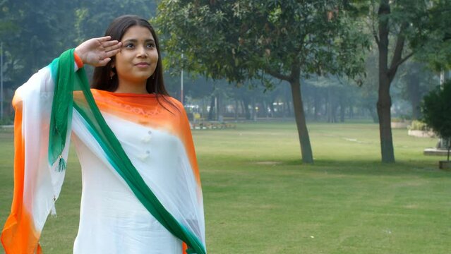 A beautiful teenage girl saluting the Indian flag on the occasion of Republic Day / Independence Day. A young female wearing a traditional dress - Tri color dress  Indian flag colors  Tricolor desi...