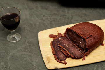 sliced basturma on a plate next to a bottle of wine and a glass