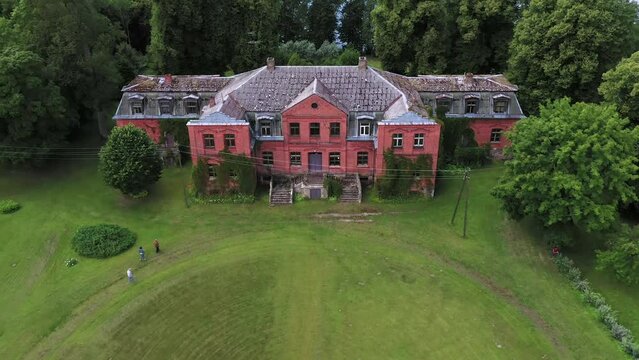 Old abandoned red brick manor of Katvari, aerial fly away view