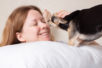 dog kisses happy woman in bed, sleep with pet, love and friendship with animals