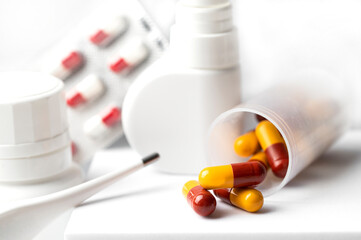Close up of Flue and cold treatment, nose spay, medical pills, vitamin suplemet capsule and thermometer on white background.