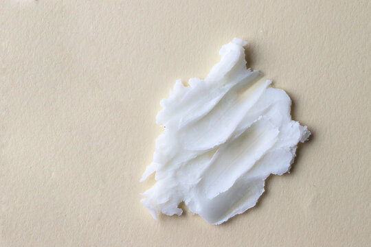 White creamy texture of clean cleansing butter on beige background.Cosmetic swatch