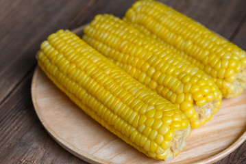 cooked sweet corn on wooden plate background, ripe corn cobs steamed or boiled sweetcorn for food...