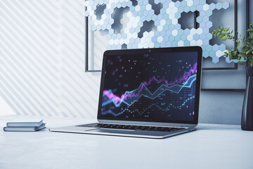 Close up of laptop with abstract glowing candlestick forex chart with index and grid on modern workplace background. Invest, trade, finance ans stock market concept. 3D Rendering.