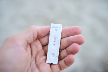 Close up hand holding rapid covid -19 test with a positive result outdoor