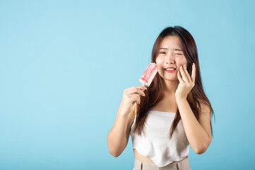 Portrait of Asian young woman with sensitive teeth after eating delicious ice cream wood stick...