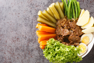 Selat Solo Javanese dish of braised beef steak in sweet soy sauce with eggs, potatoes and vegetables closeup in the bowl on the table. Horizontal top view from above