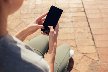 Low section of woman using phone while sitting on seat - Powered by Adobe
