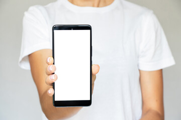 A girl in a T-shirt on a white background in her hand holds a mobile phone with a white screen, a template with a phone, a white screen