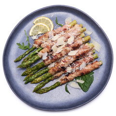 Healthy food - Asparagus wrapped with bacon and spices on a plate isolated on white background