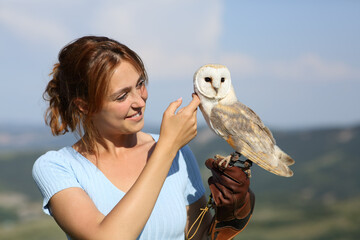 Happy falconer caressing an owl in nature
