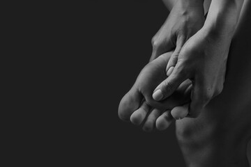 hands doing leg massage closeup on dark background, leg pain concept