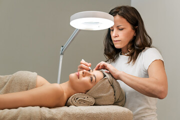 Beautician correcting eyebrows of client