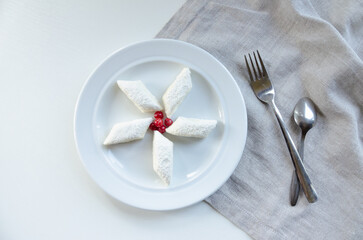 dumplings on a plate next to a fork and a spoon, composition on a light background