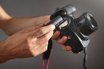 Naklejka premium Photographer inserting battery to the camera.