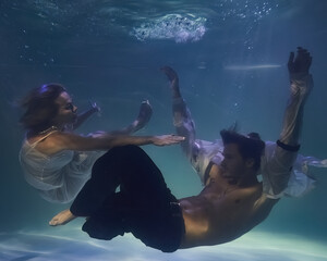 fashionable man in a white shirt and a woman in a white dress underwater in the pool