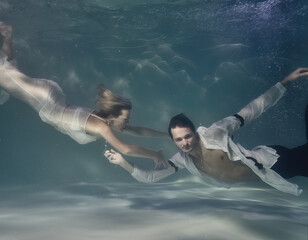 Fototapeta na wymiar fashionable man in a white shirt and a woman in a white dress underwater in the pool