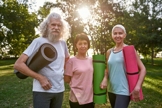 Elderly friends look at camera on meadow in park