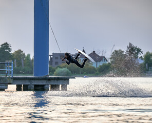 Wakeboarder making tricks while wakeboarding on lake. Young man surfer having fun wakesurfing in...