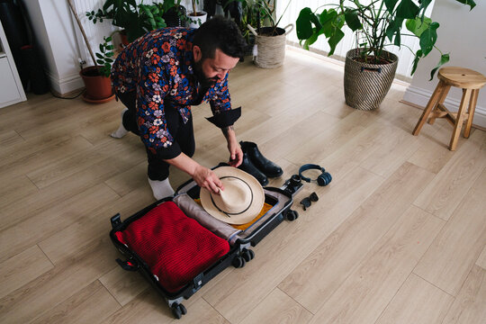 Mature man packing suitcase at home