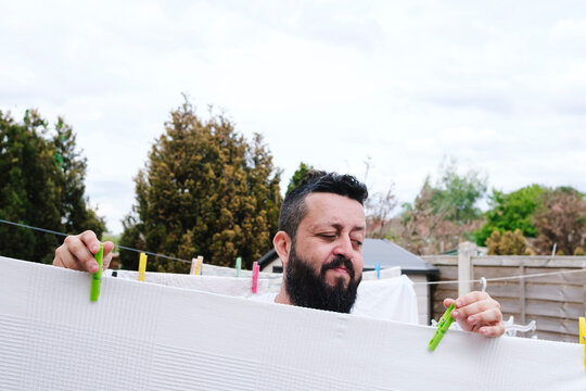 Man with clothespin drying sheets at back yard